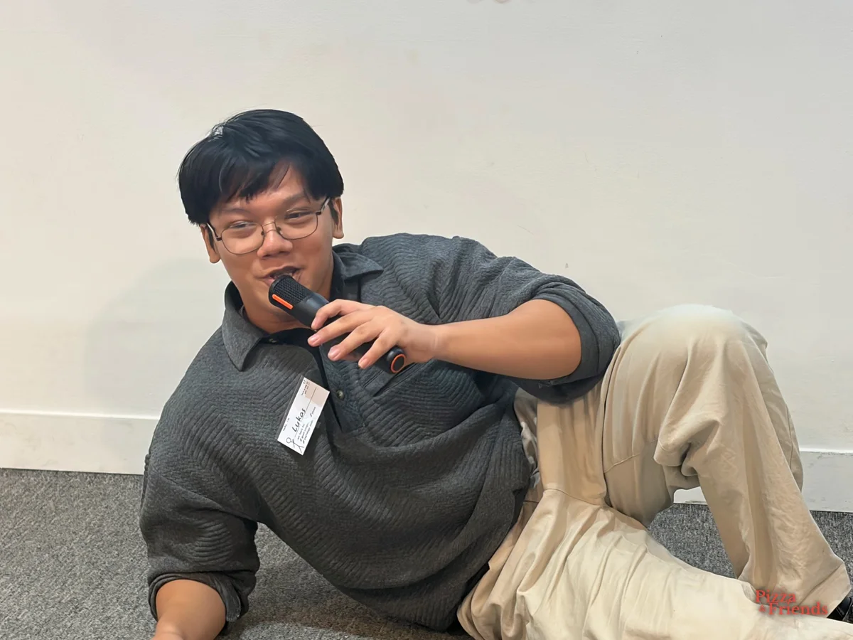 A participant lounges on the floor and grins while talking into a mic.